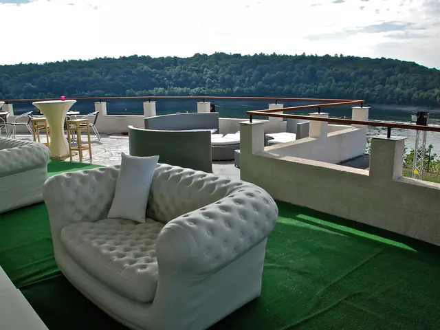 There are many sofas. On the sofa there is a pillow. There is a green carpet. On the background...