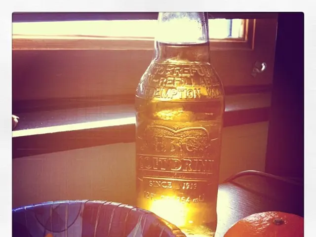 In the image we can see there is a bowl in which there are snacks and on the table there is a wine...