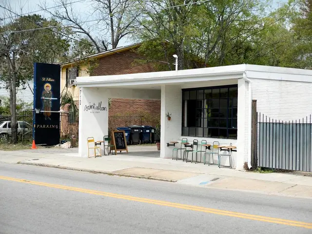 A restaurant by the side of road with some tree in the background.