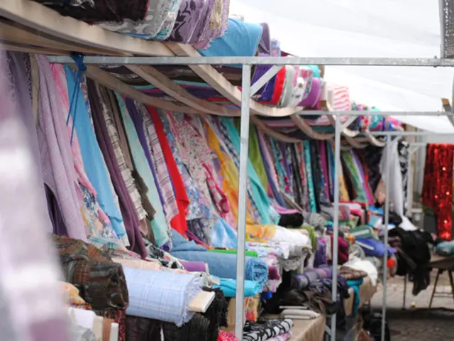 In this image I can see the clothes which are colorful. These clothes are under the tent.
